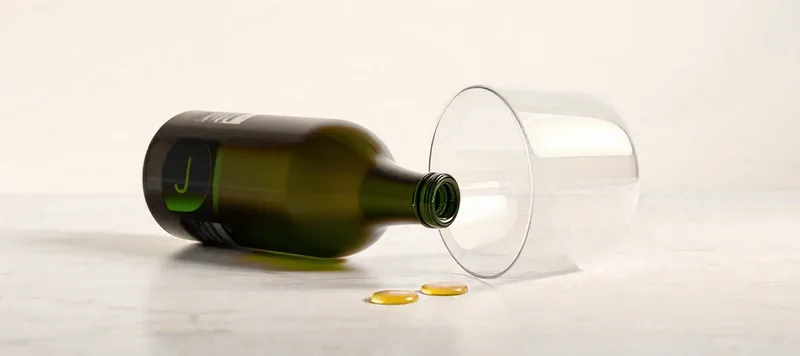 Une bouteille de vin vide couchée et un verre renversé, quelques gouttes sur le marbre.